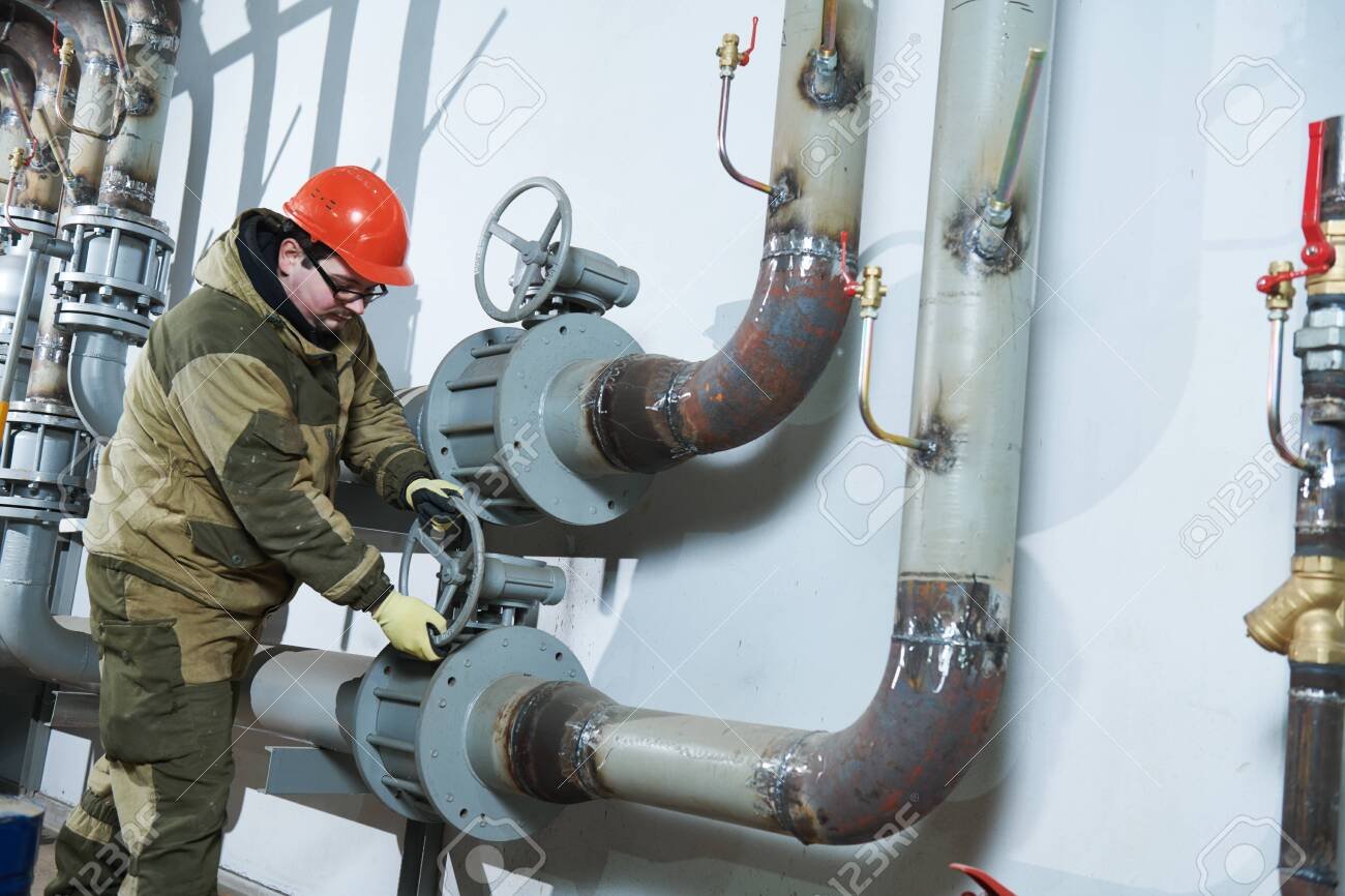 industrial plumber assembling pipes, valves, faucets in water circulation room
